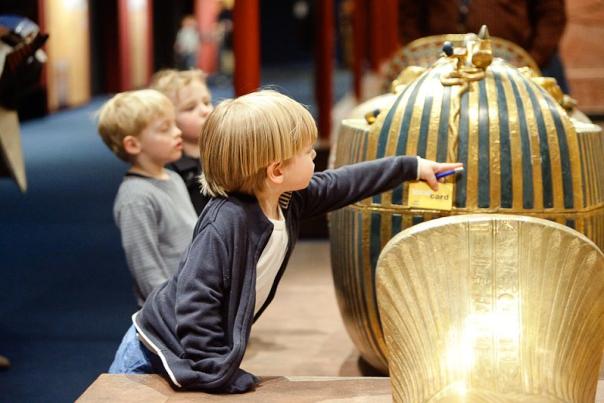 Three small boys point to a sarcophagus at the 'Tutankhamun' exhibit in COSI.