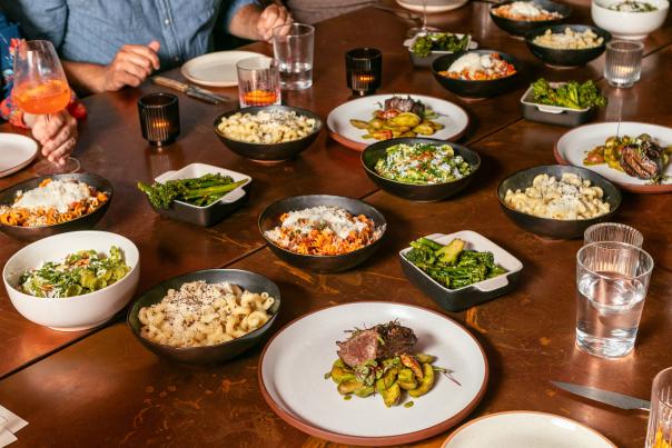 Several colorful plates of food sit on a wooden table