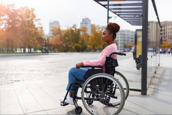 Woman in wheelchair waiting at a bus stop