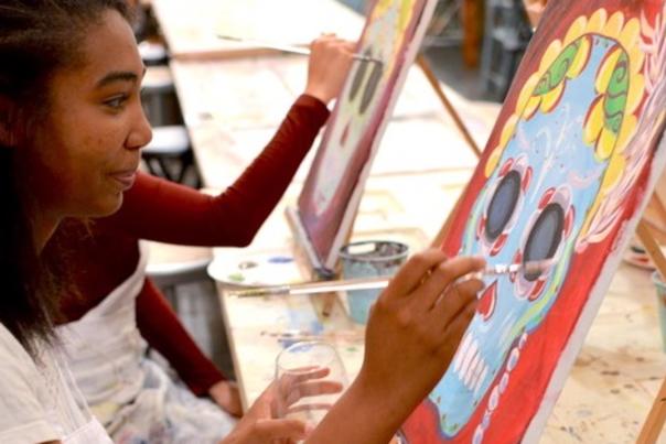 Two girls painting sugar skulls on canvases during a class at Studio 614