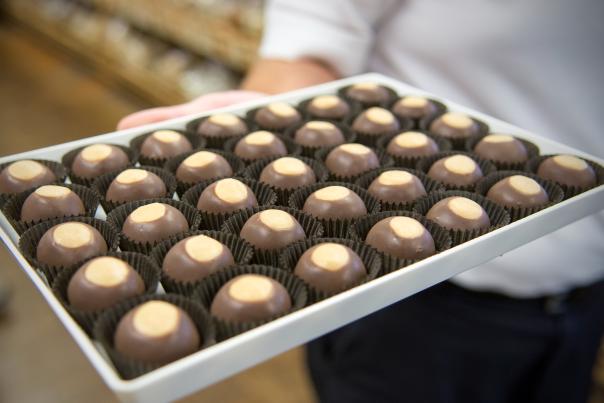 A woman's hand holds a tray of buckeye candies