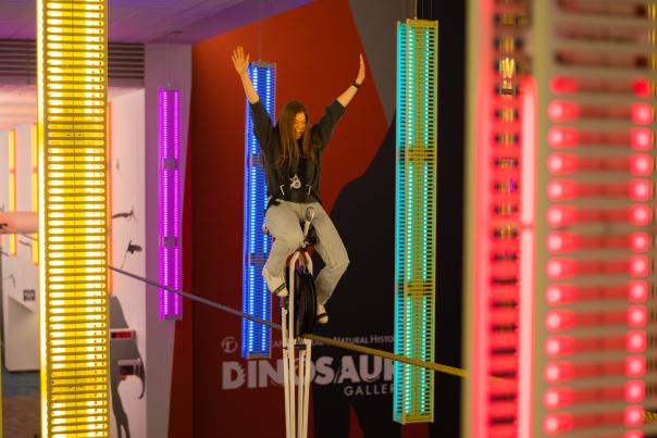 Woman riding high-wire unicycle at COSI