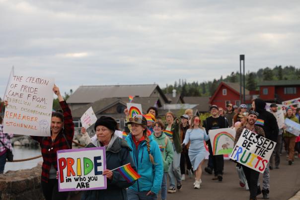 A group of people walking down the street with pride flags