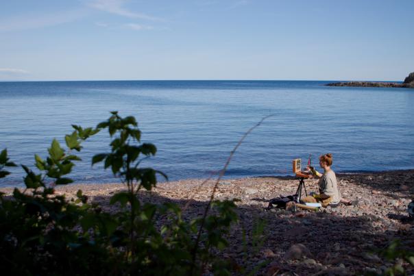 A plein air artist painting on the shores of lake superior
