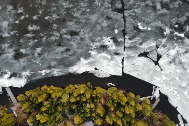 An aerial photo of a shoreline with ice melting and moving out.