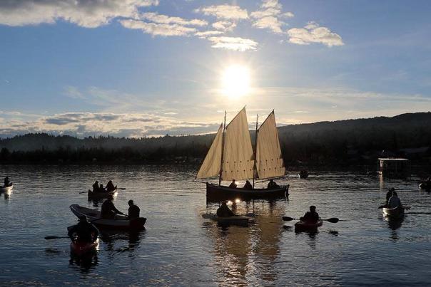 A group of boaters and sailors on a lake.