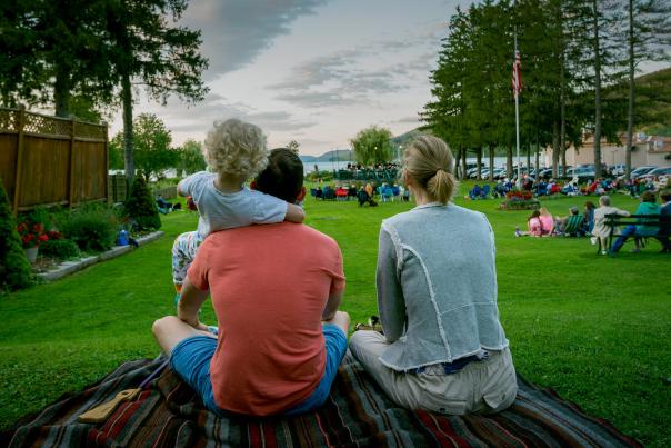a family sitting on the grass in front of a lake