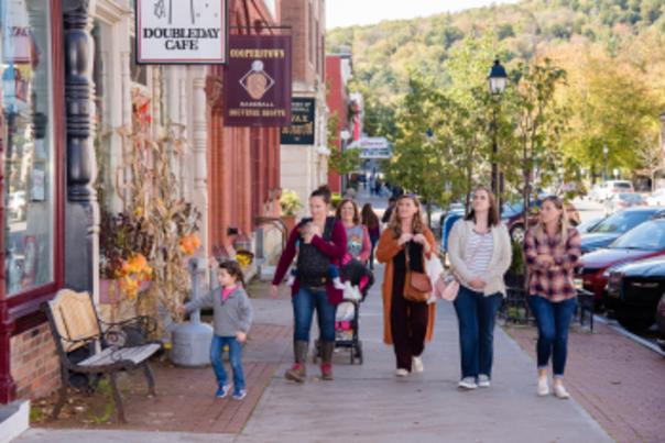 A family walking down main street in Cooperstown during fall.