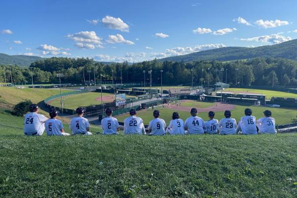 A youth baseball team sitting on a hill overlooking baseball fields