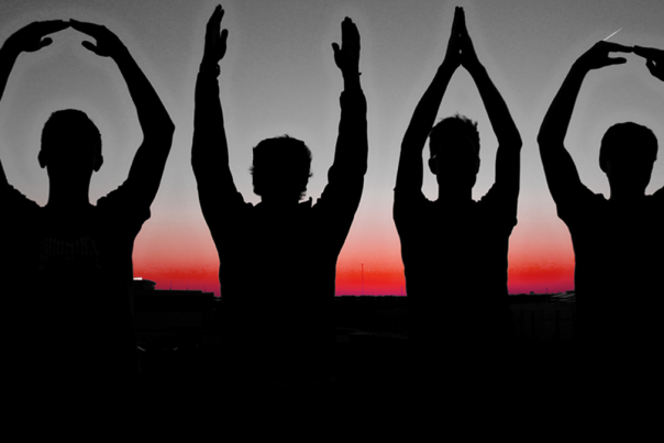 Four silhouetted individuals creating O-H-I-O with their arms.