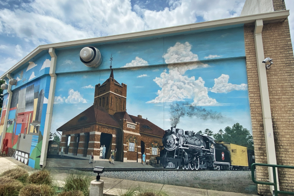 A mural on the side of a building of a train station