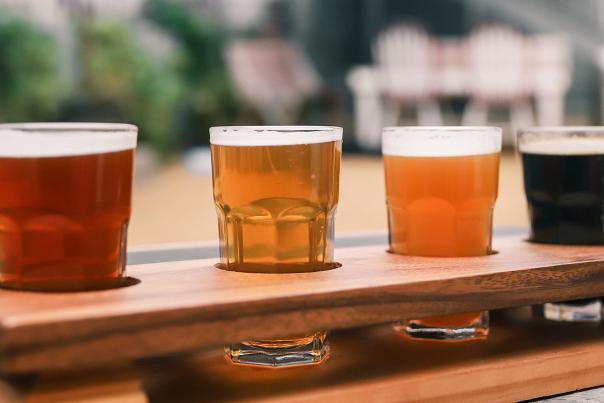A flight of beer sits on a table at an outdoor bar.
