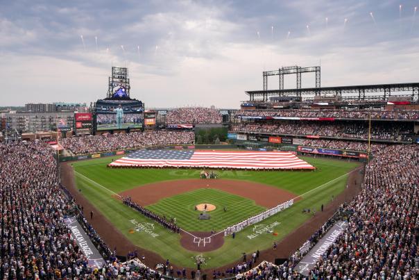 A massive American flag is opened on Coors Field while fireworks go off at the Denver MLB All-Star Game