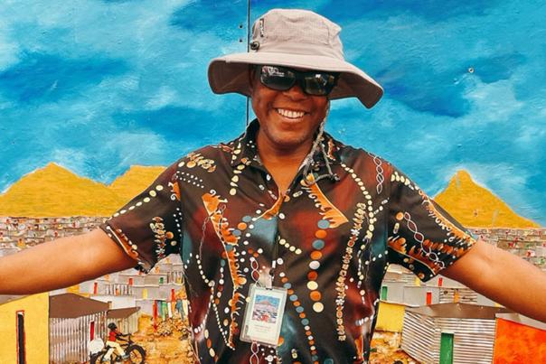 An artist stands in front of a painting at the Cherry Creek Arts Festival in Denver, Colorado.
