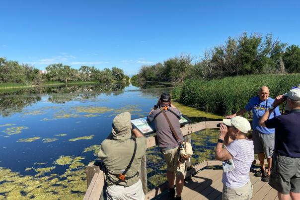 A small crowd on a dock overlooks the lake at Bluff Lake Nature Center in Denver, Colorado..
