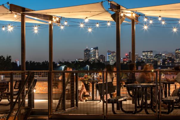 People sitting on the rooftop of BurnDown and enjoying the Denver skyline in twilight.