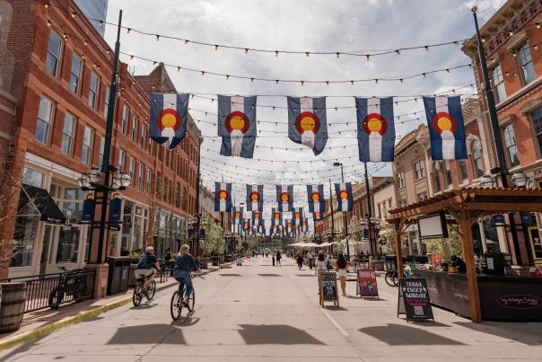 A wide view of Larimer Square in Denver, Colorado, where people are walking and riding bikes.