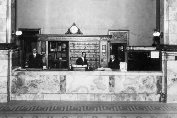 A black-and-white, historical photo of the Brown Palace check in desk