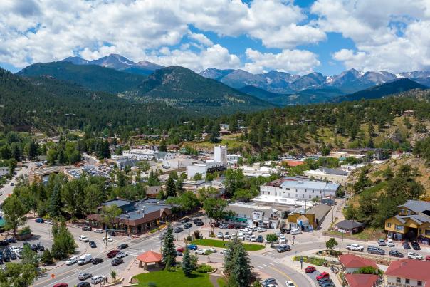An aerial view of Estes Park with soaring mountains and fluffy clouds in the background