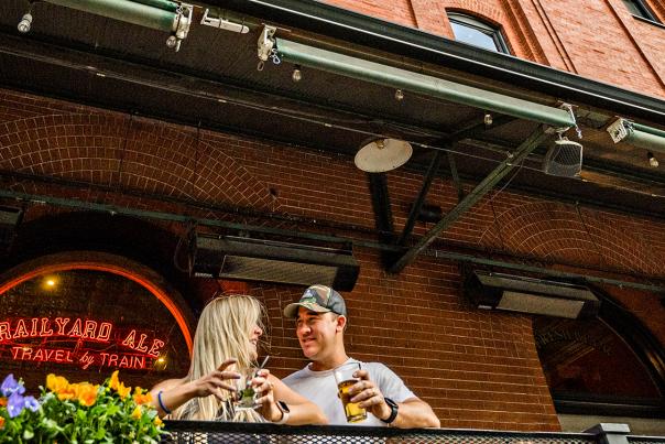A couple stands outside Wynkoop Brewing Company's brick facade in Denver, Colorado.