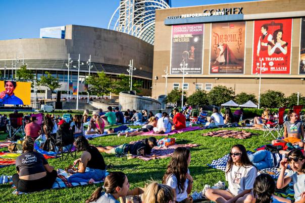 People gather on a green lawn watching a movie outside of the Arts Complex