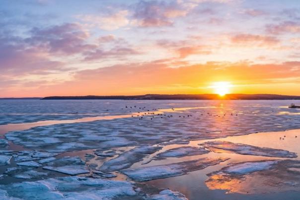 Devils Lake, ND sunrise showing melting lake ice with open water showing through.