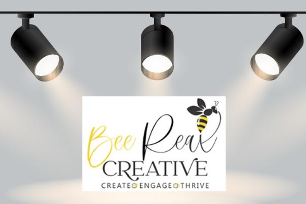 Text reading "Bee Real Creative" with a bumblebee under spotlights