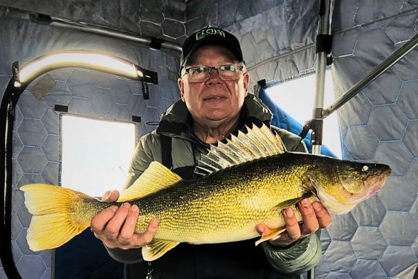 Man holding large walleye in pull over tent ice fishing on Devils Lake, North Dakota