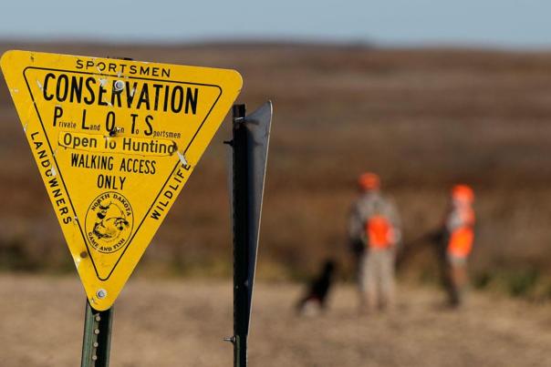 Yellow huning plot sign in Devils Lake, ND with bird hunters in the background