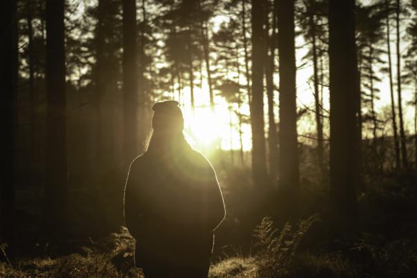 person wearing a bobble hat in the sunset at haldon forest