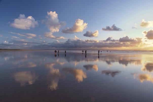 people at saunton beach in the sea at sunset