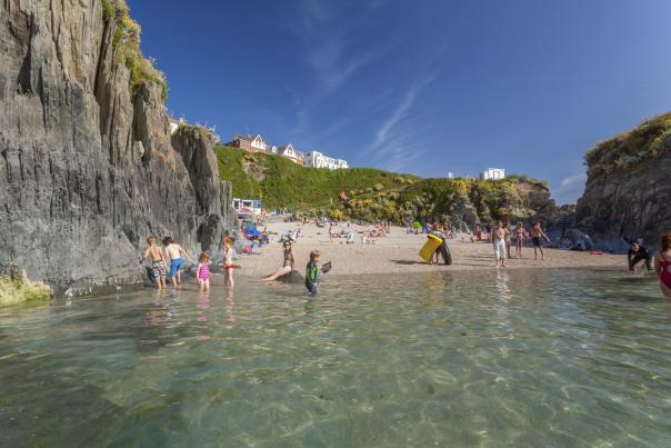 a beach in woolacombe with people swimming and enjoying the sun