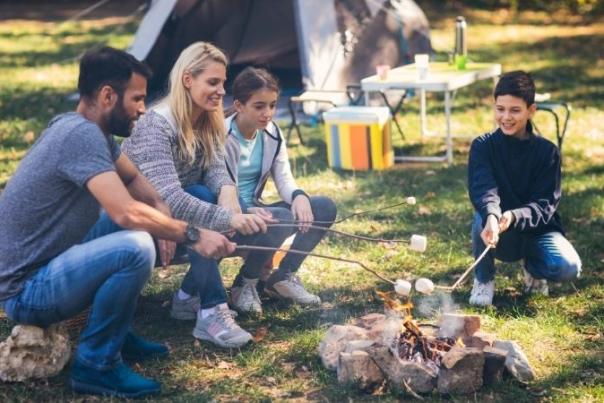 group of people roasting marshmallows next to their tent