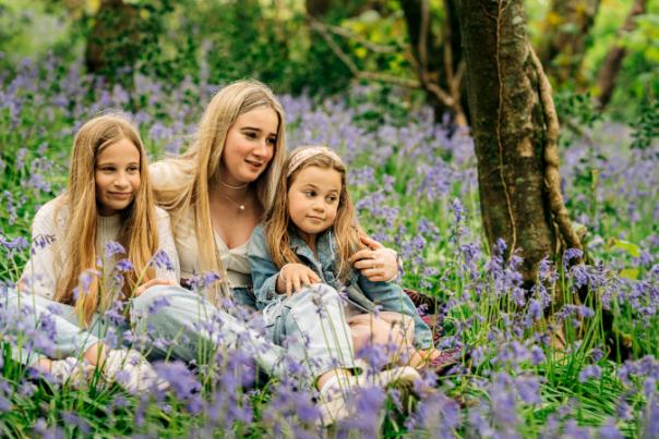 three young women sitting among bluebells