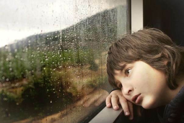 child looking out of the window in the rain