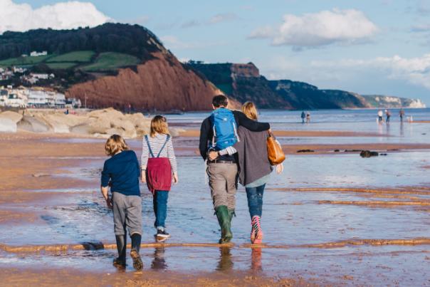 family walking along sidmouth beach
