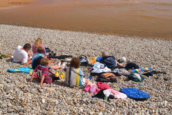 image shows family on sidmouth beach