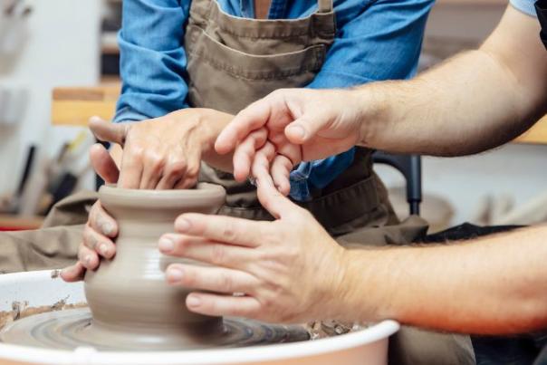 image shows two people learning how to use pottery