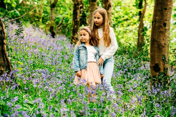 two girls stood in bluebells with trees