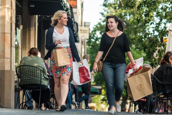 People Walking Down Sidewalk With Shopping Bags