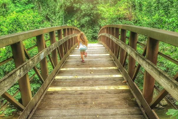 Little Girl Running Down A Wooden Bridge In Sand Island Park