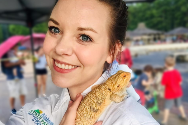 Anna Jones smiles at the camera while holding a lizard from the Oak Mountain State Park Interpretive Center.