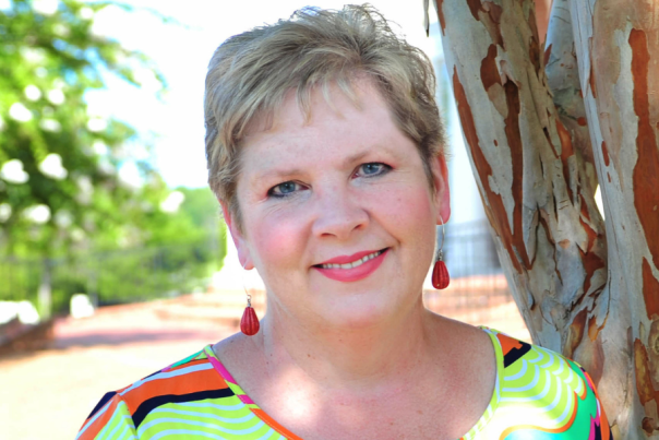 Melanie Poole smiles in front of a tree at American Village in Montevallo, Alabama.