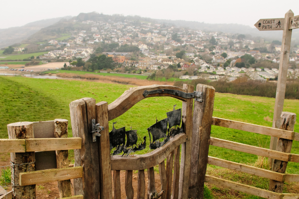 Picture showing sculpture on a gate overlooking Golden Cap on a misty day