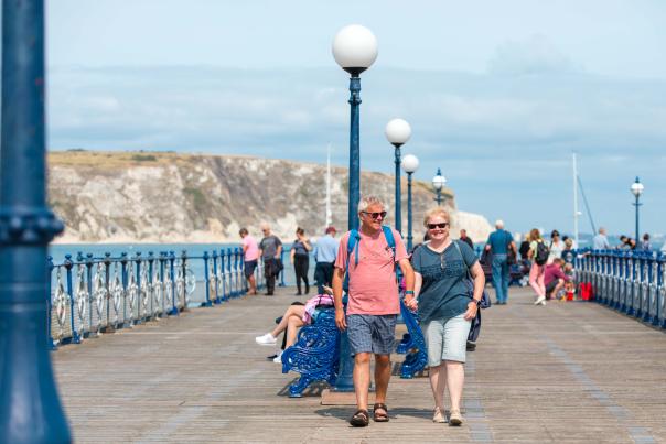 Man and woman walking along Swanage Pier in Dorset