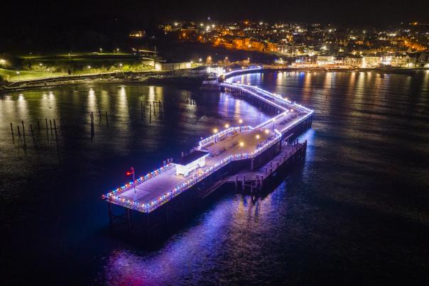 Swanage Pier lit up with multi-coloured lights during the Lighting Up Lives event at Christmastime