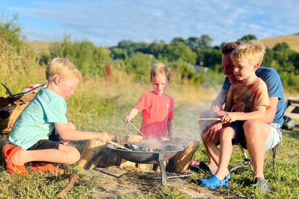 A father and three boys cooking on a campfire at Coppet Hill campsite in Dorset
