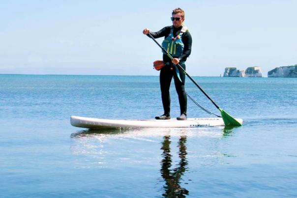 Man stand up paddleboarding at Old Harry Rocks with Fore Adventure