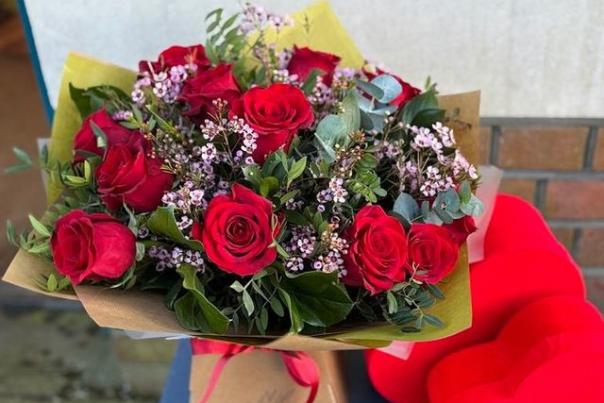 Bunch of beautiful flowers containing red roses in a brown box.