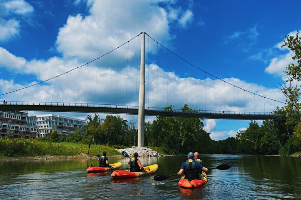 A group of people on kayaks under the Dublin Link Pedestrian Bridge.